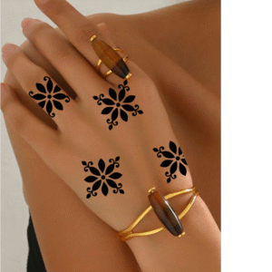 Five small black floral henna stencil motifs applied on the back of a hand and fingers, spaced evenly, styled with gold jewelry and gemstone rings.