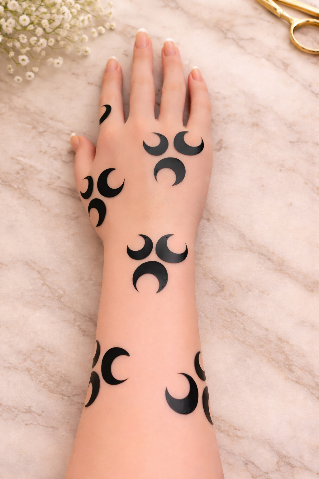 Hand with crescent moon henna stencil design on marble background with soft styling