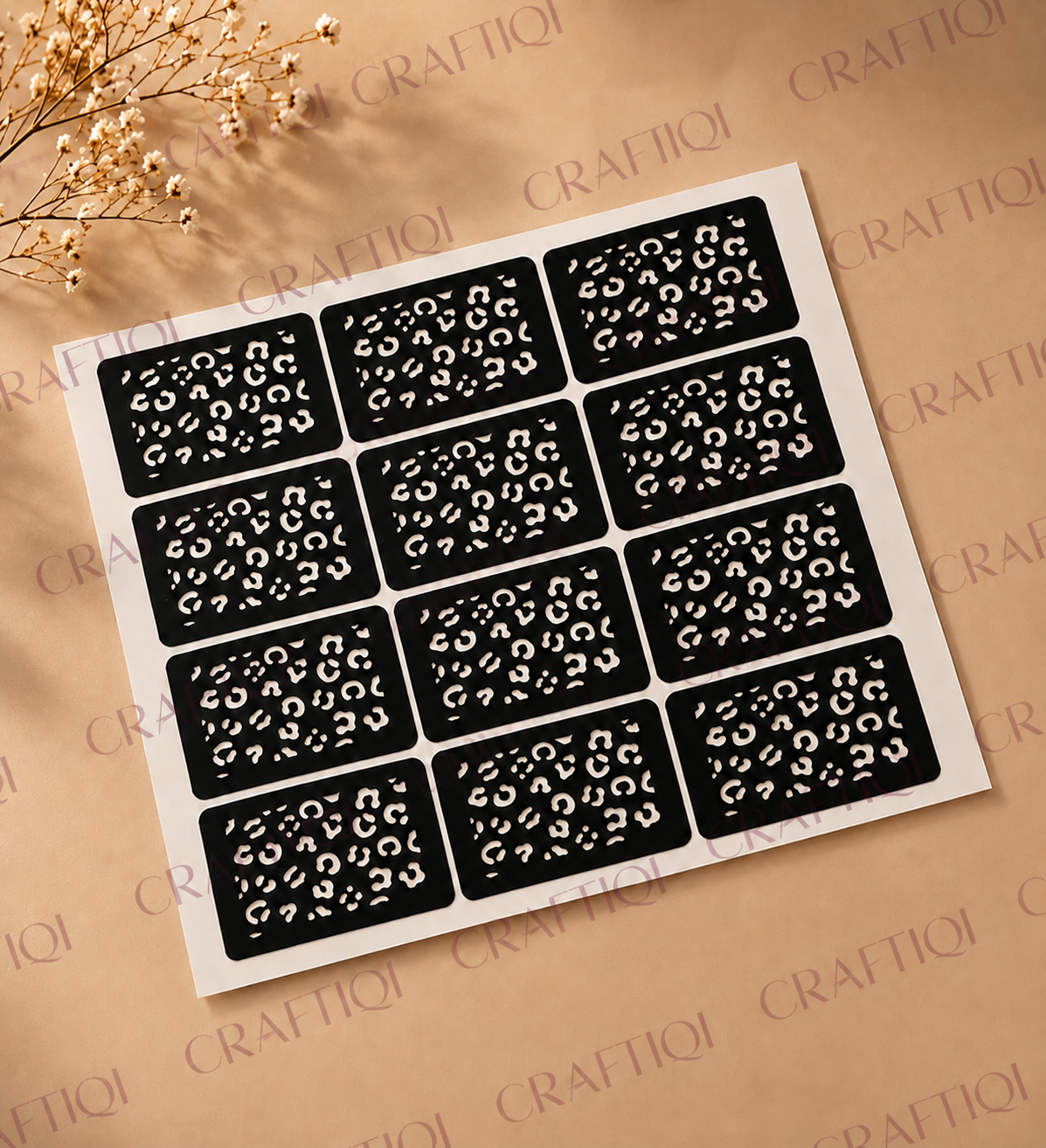 Flat lay of a henna stencil sheet featuring 12 square leopard print designs arranged in a grid on a warm beige background with dried flowers. The image includes a repeating Craftiqi watermark across the photo.